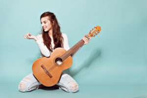 | smiling beautiful young girl posing with guitar